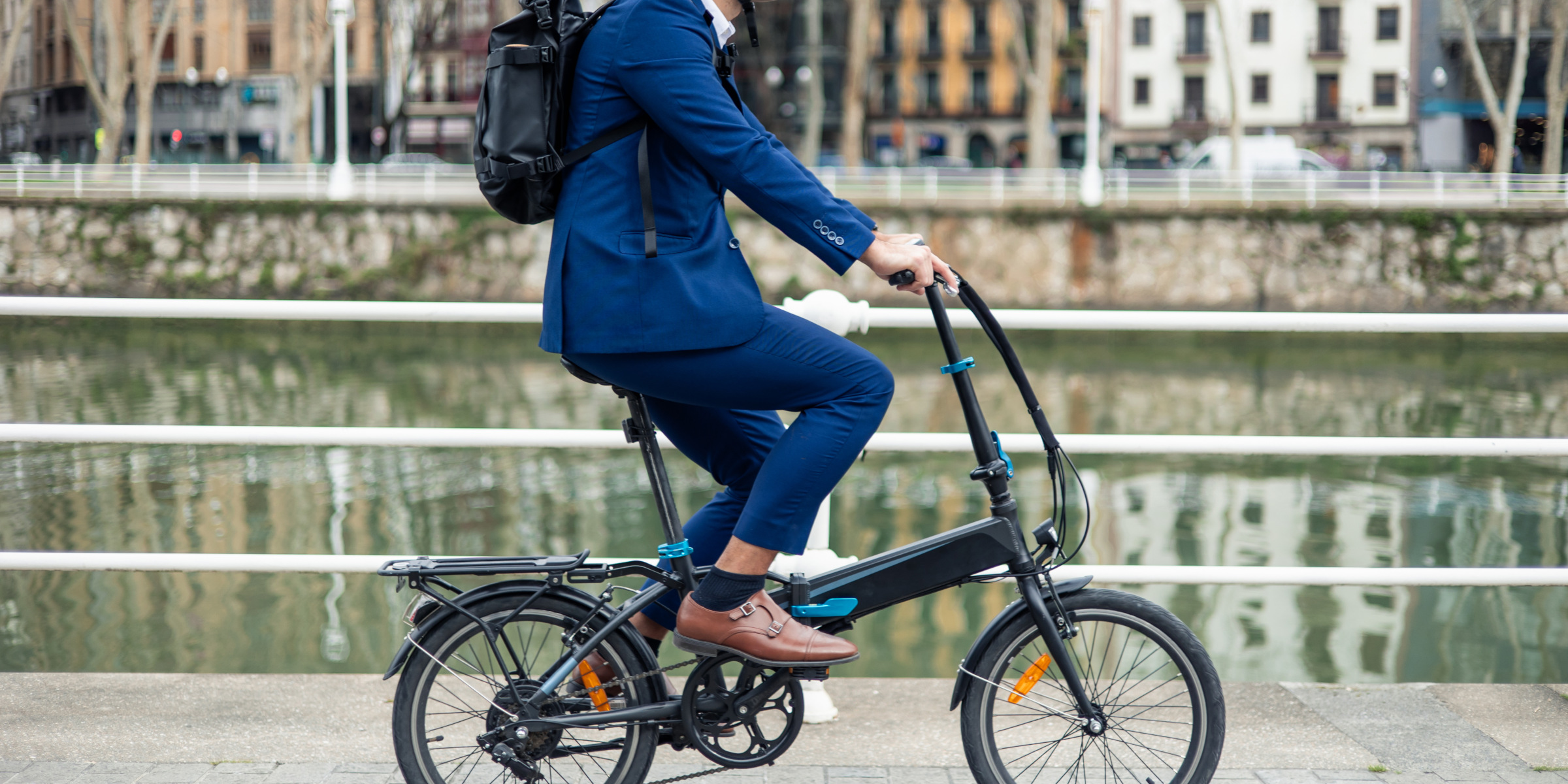 Mann fährt mit einem E-Bike zur Arbeit über eine Brücke in der Stadt