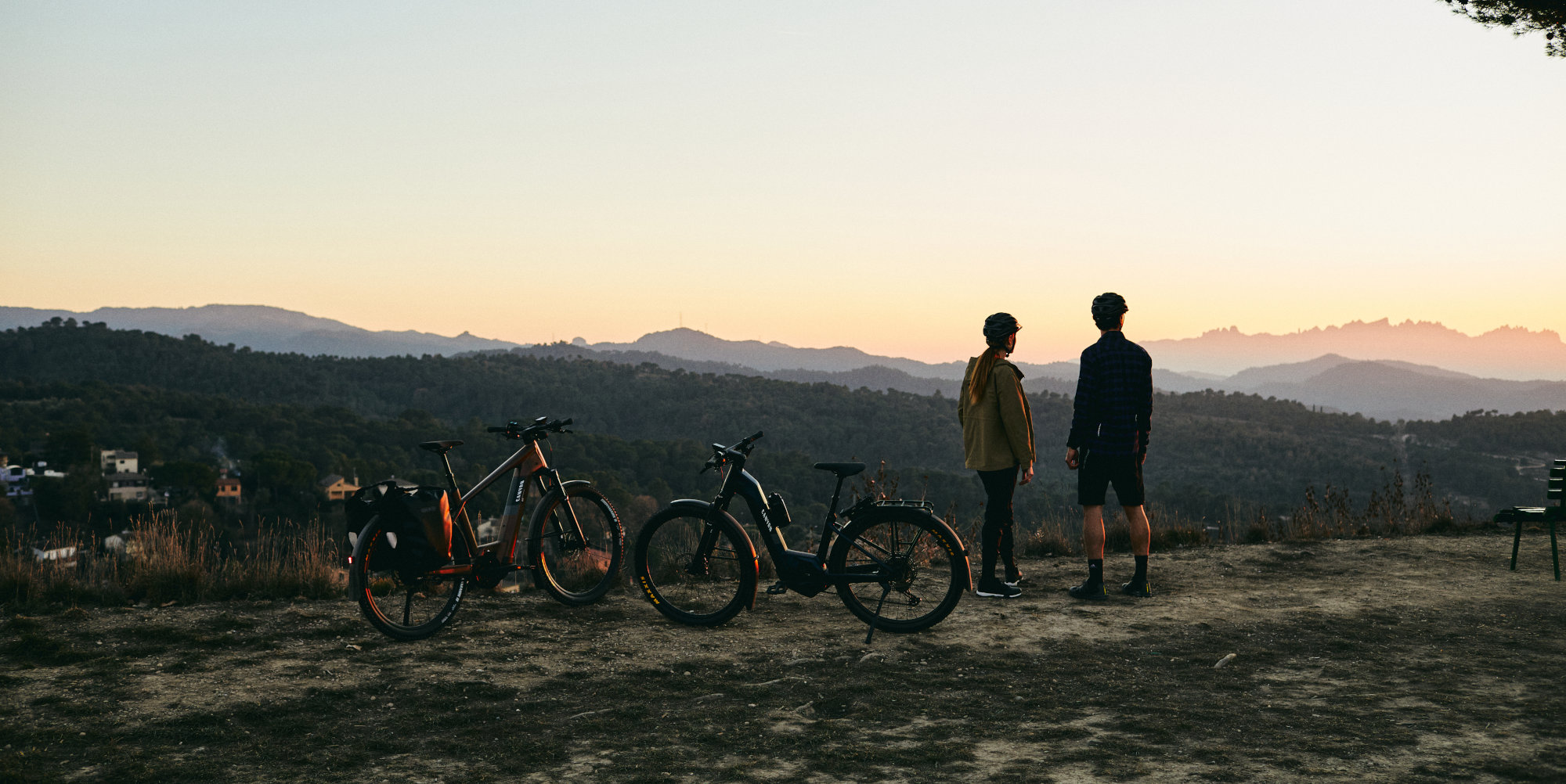 Mann und Frau mit Bikes schauen Sonnenuntergang an.