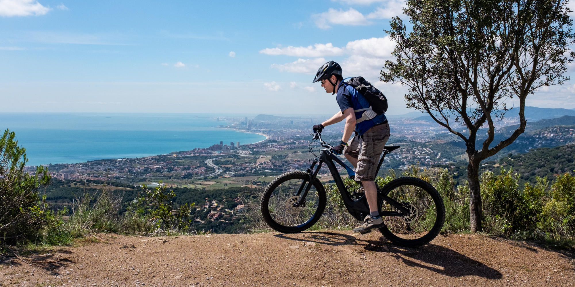 Mann auf E-Bike Fully steht an Aussichtspunkt.