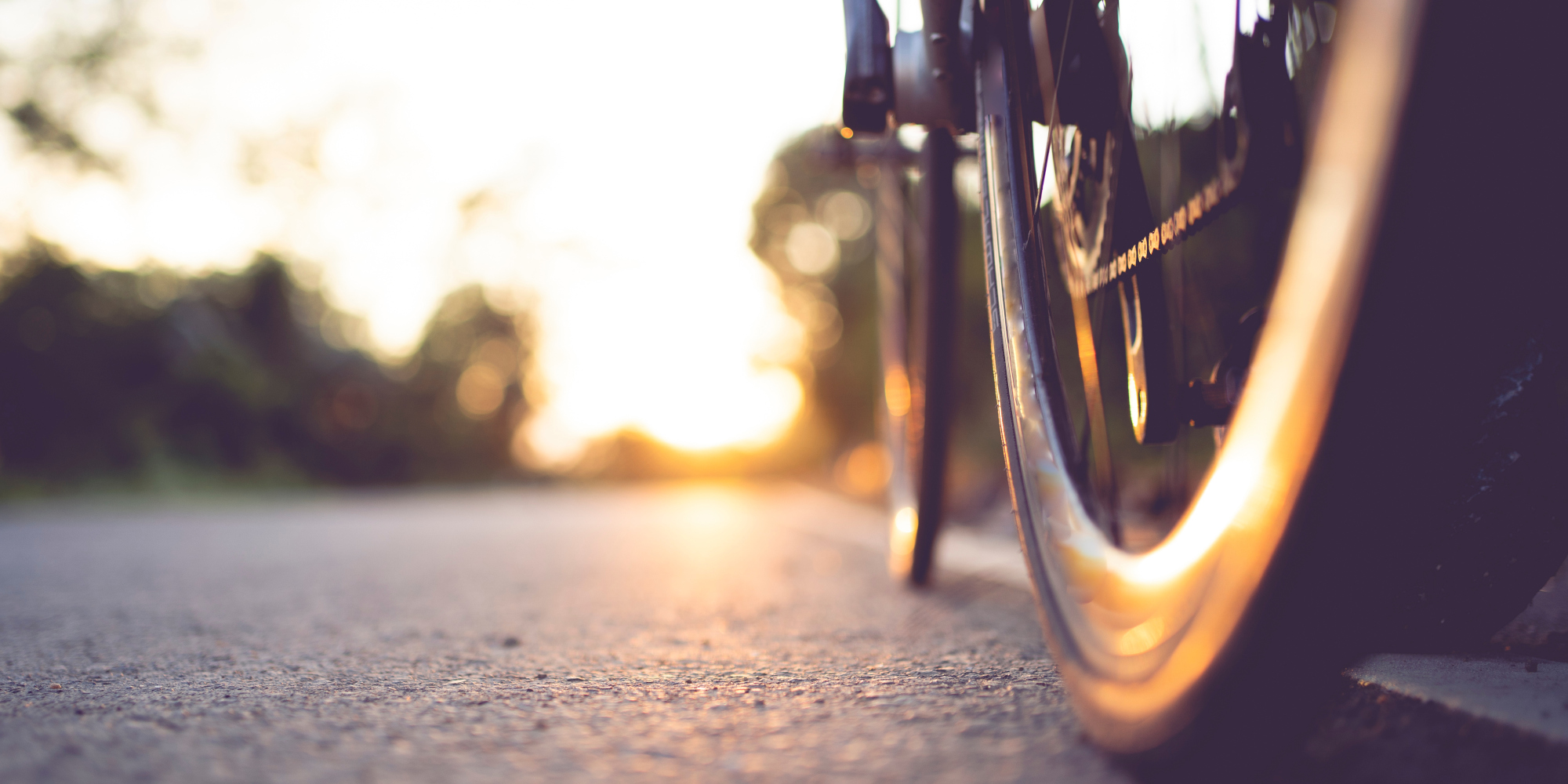 Nahaufnahme eines Rads an einem Fahrrad, dass über eine Straße fährt