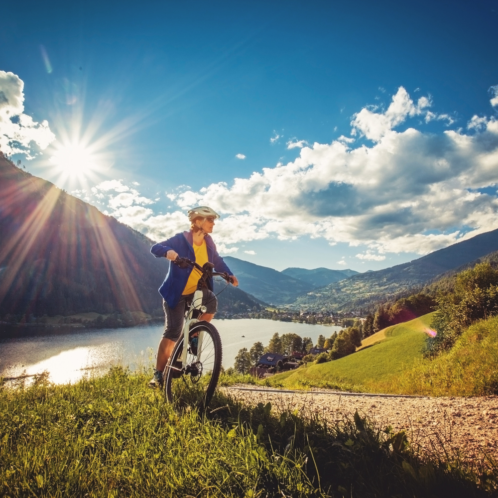 Eine Frau fährt mit dem Fahrrad vor einem See entlang