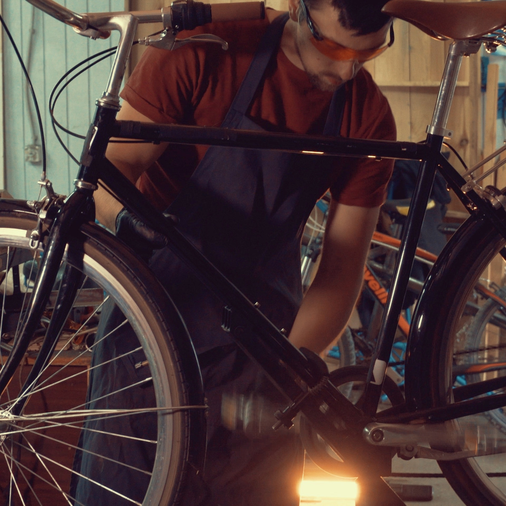 Ein junger Mann schraubt an einem Fahrrad in einer Werkstatt.