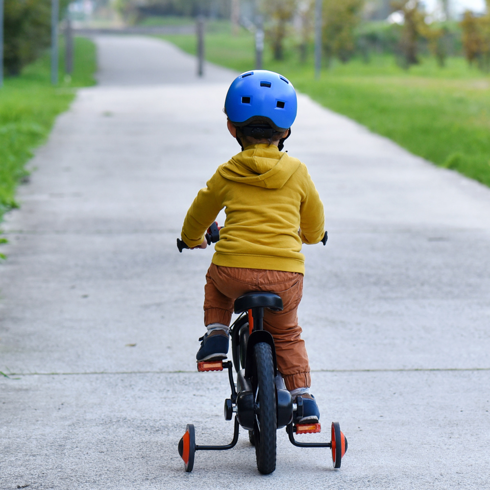 Kind fährt auf einem Fahrrad mit Stützrädern