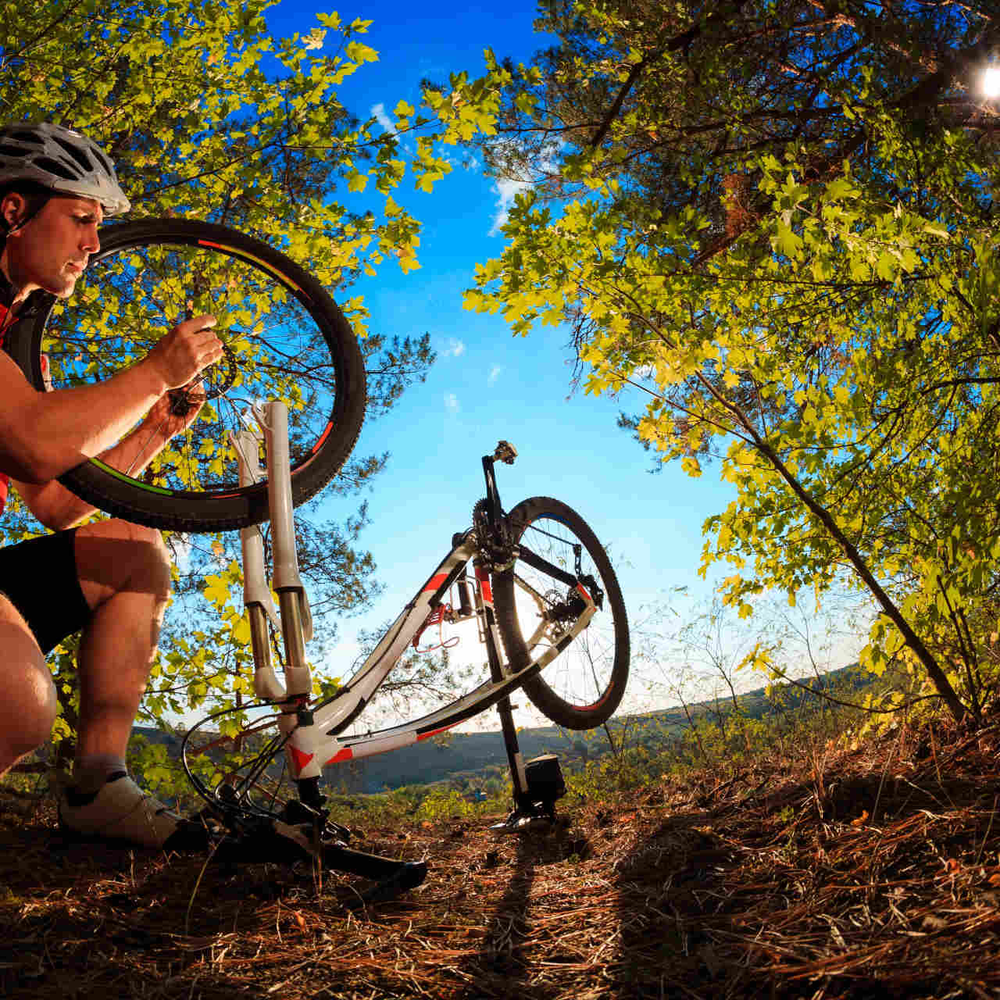 Mann repariert Fahrrad im Wald