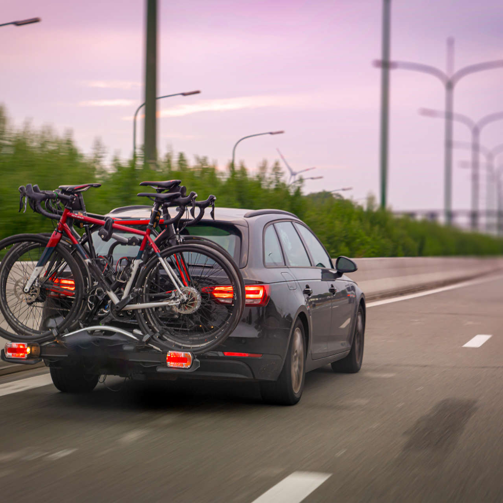 Auto fährt auf der Straße. Am Heck des Autos ist ein Fahrradträger befestigt.