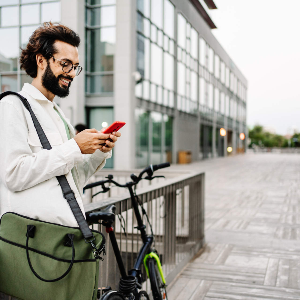 Mann steht neben Rad mit Handy in der Hand