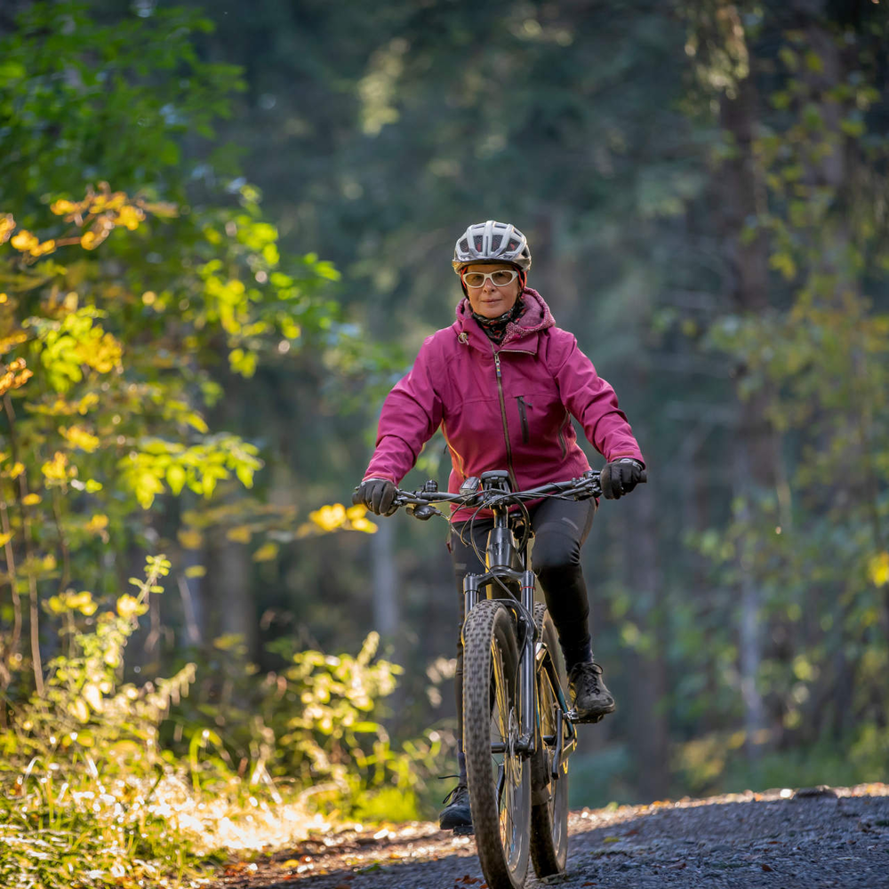 Eine Frau fährt im Wald ihr E-Bike