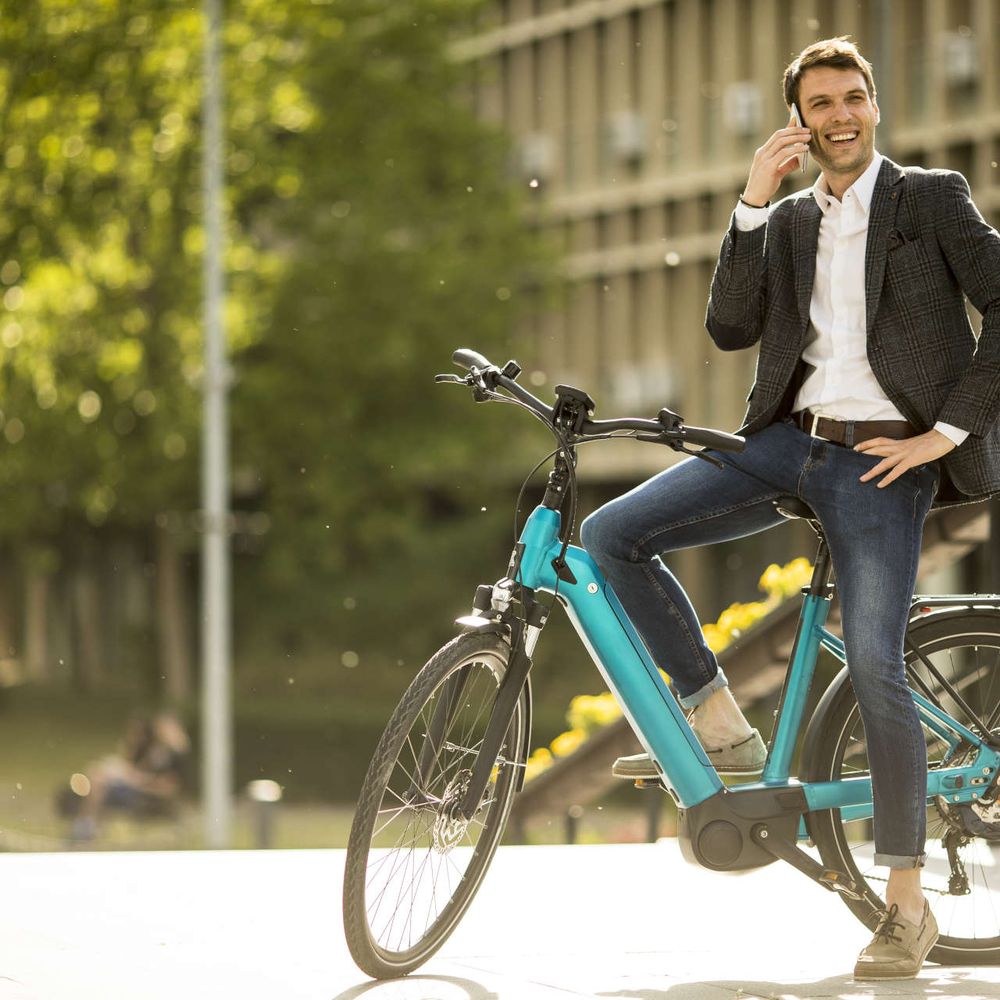 Mann sitzt auf einem stehenden Fahrrad und telefoniert