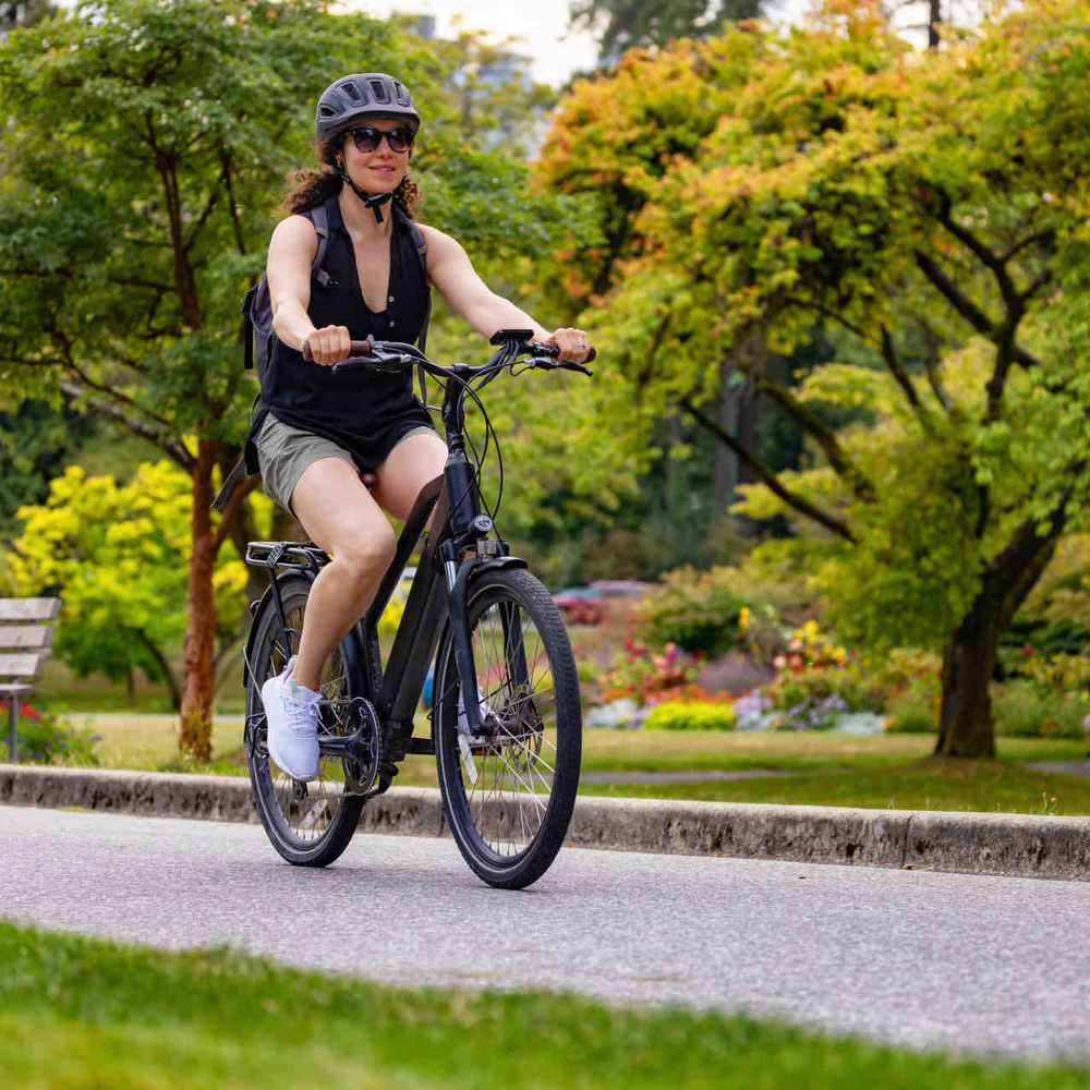 Frau auf Fahrrad fährt durch Park.