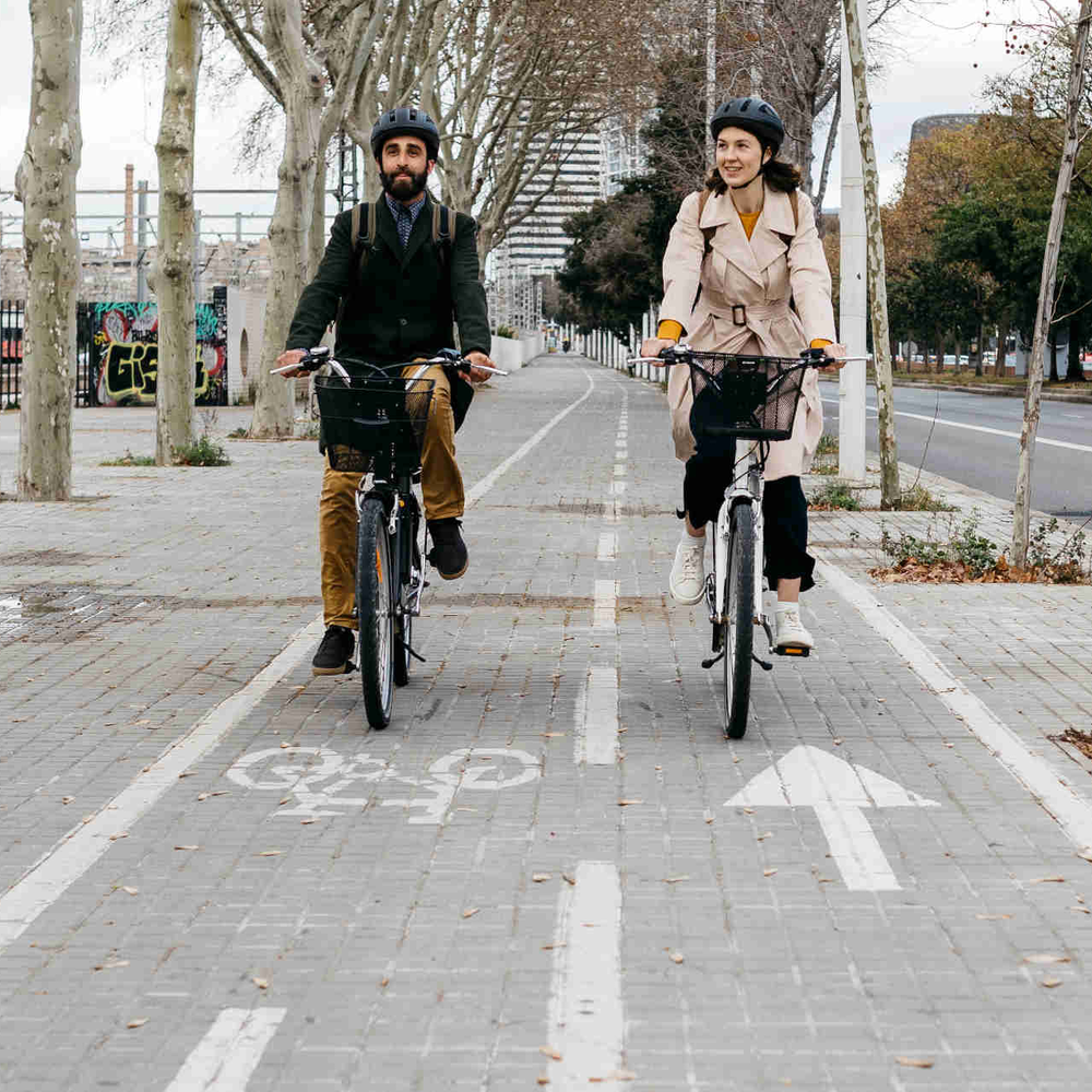 Zwei Personen fahren nebeneinander auf Fahrrädern über einen Radweg.