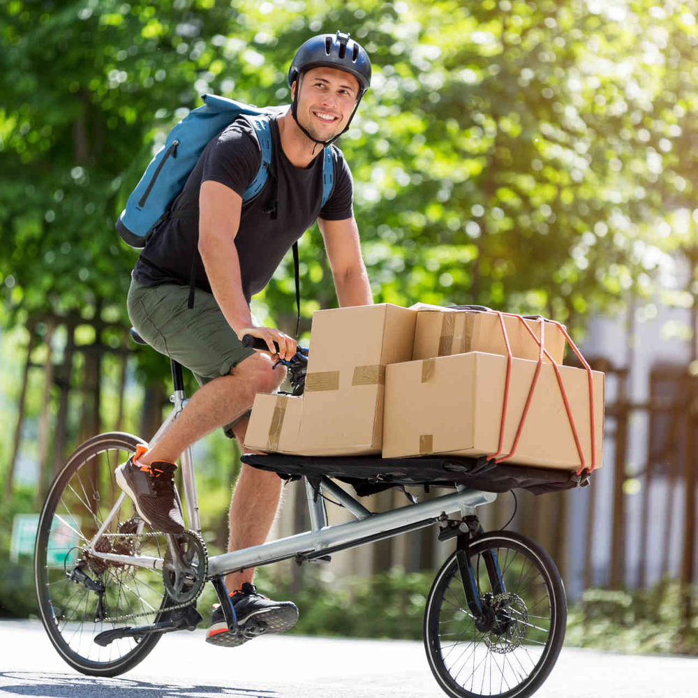 Man fährt auf Cargo-Bike beladen mit Kartons