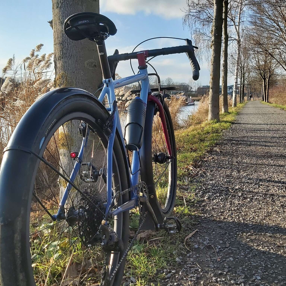 Ein Gravel Bike von hinten fotografiert auf einem Schotterweg bei sonnigem Winterwetter..