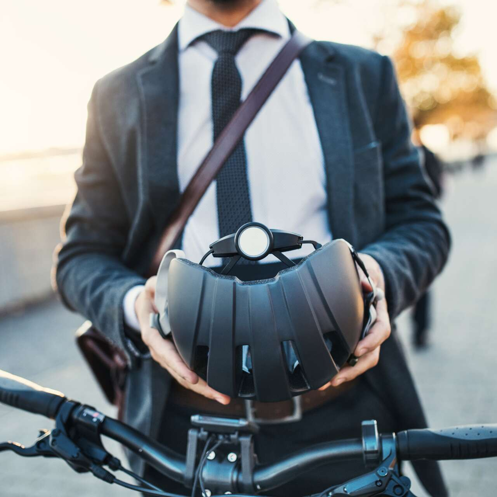 Mann steht neben Pedelec und hält seinen Helm in der Hand