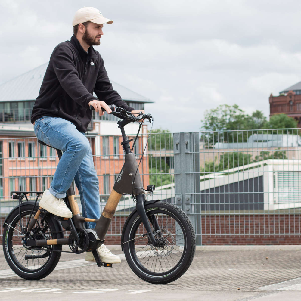 Mann fährt auf Parkhaus mit Bambus E-Bike.