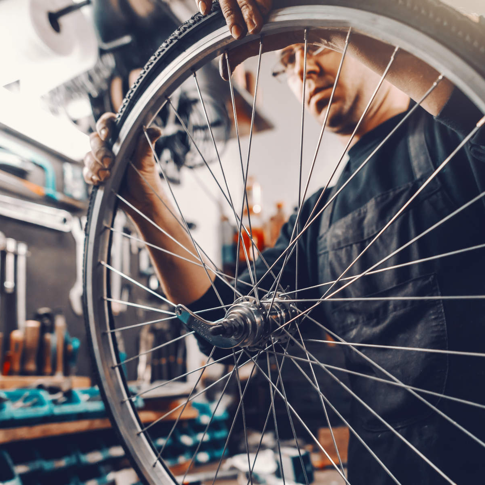 Mann untersucht Fahrrad Reifen.