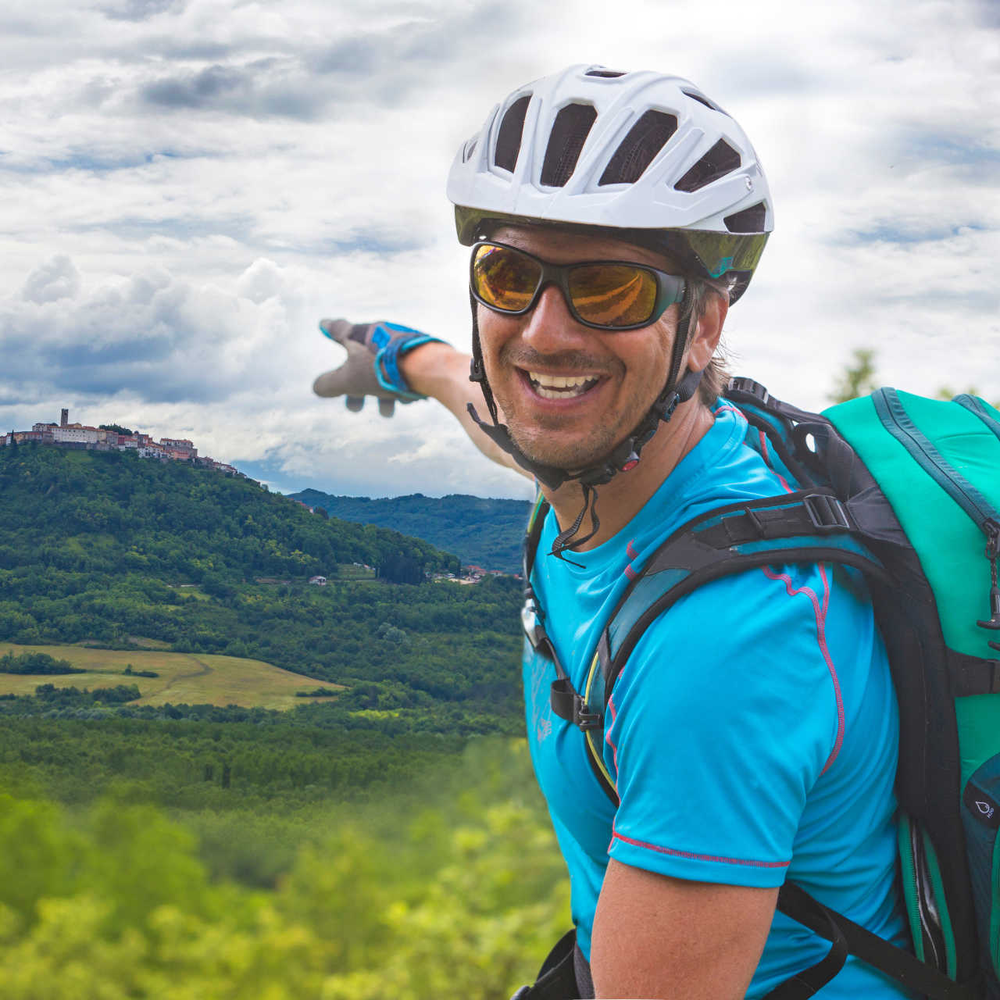 Mann fährt mit Fahrrad durch Slowenien und zeigt auf Landschaft