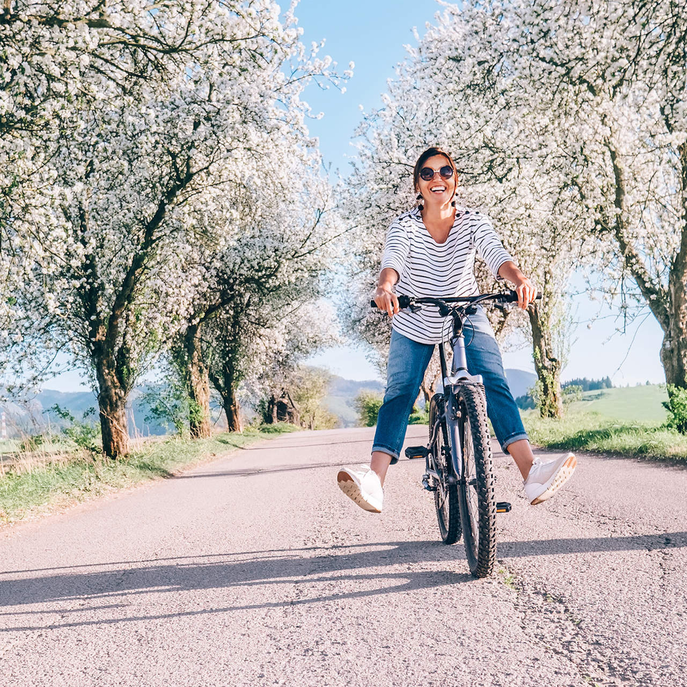 Frau fährt lachend auf dem Fahrrad im Frühling