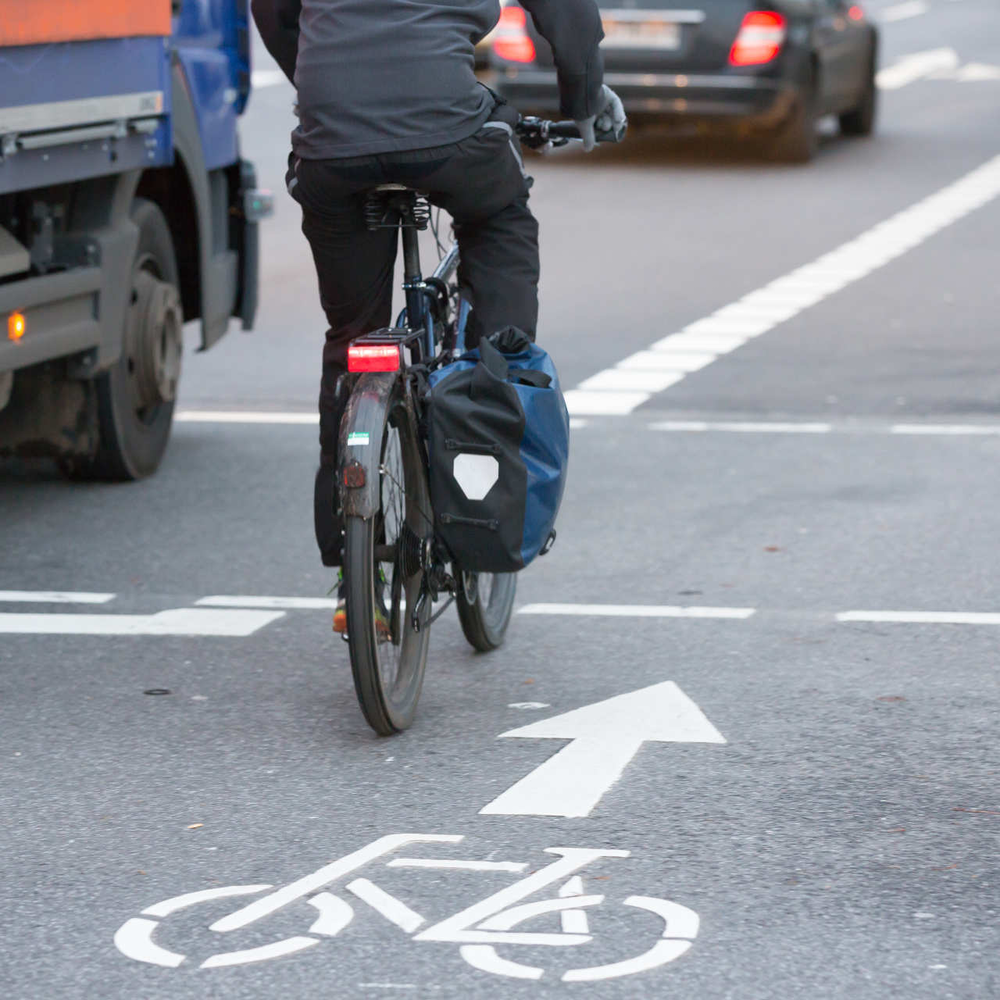 Fahrradfahrer fährt mit eingeschaltetem Rücklicht durch Straßenverkehr