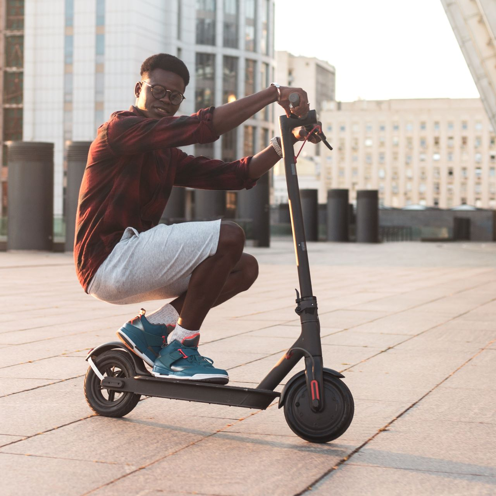 Mann fährt auf E-Scooter in der Hocke