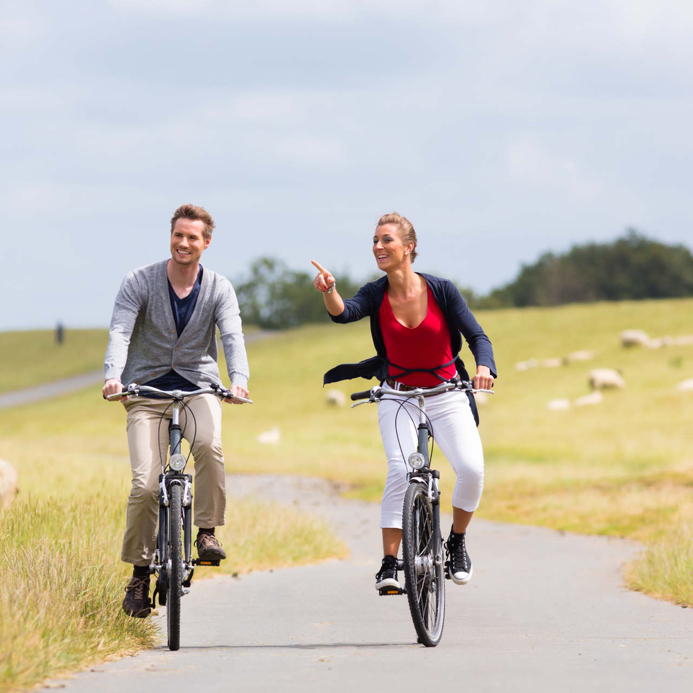 2 Fahrradfahrer auf Radweg zwischen einem Feld