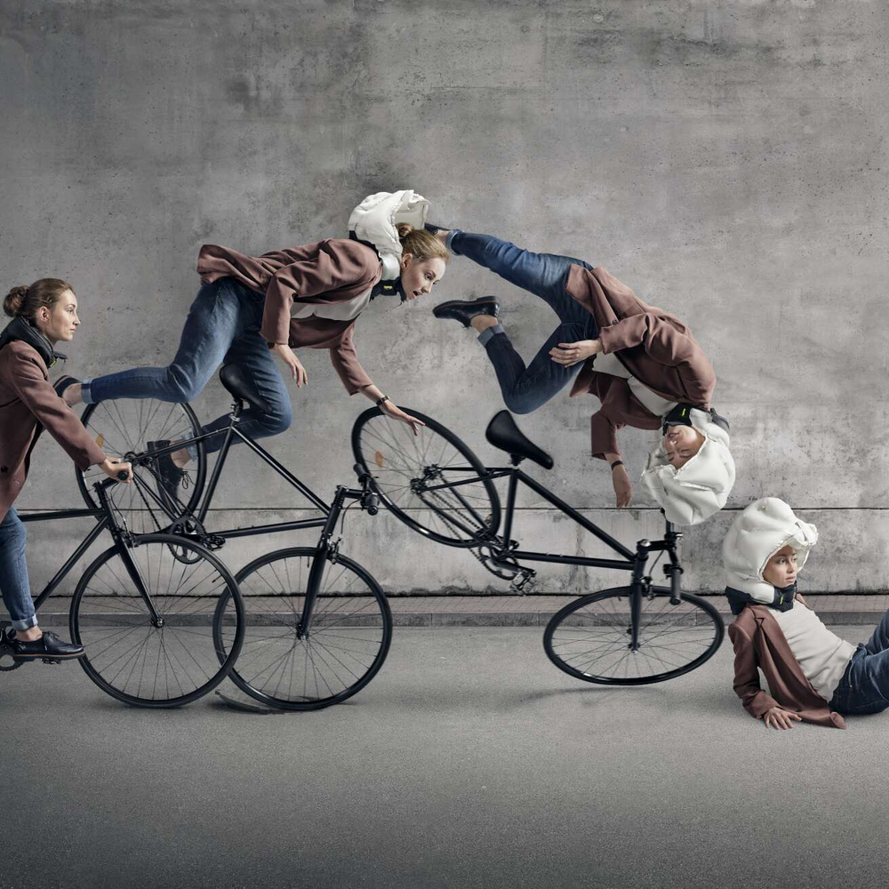 Eine Frau fällt vom Fahrrad und trägt einen Airbag-Helm