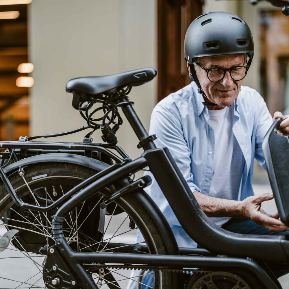 Mann in der Stadt nimmt Akku aus seinem E-Bike raus